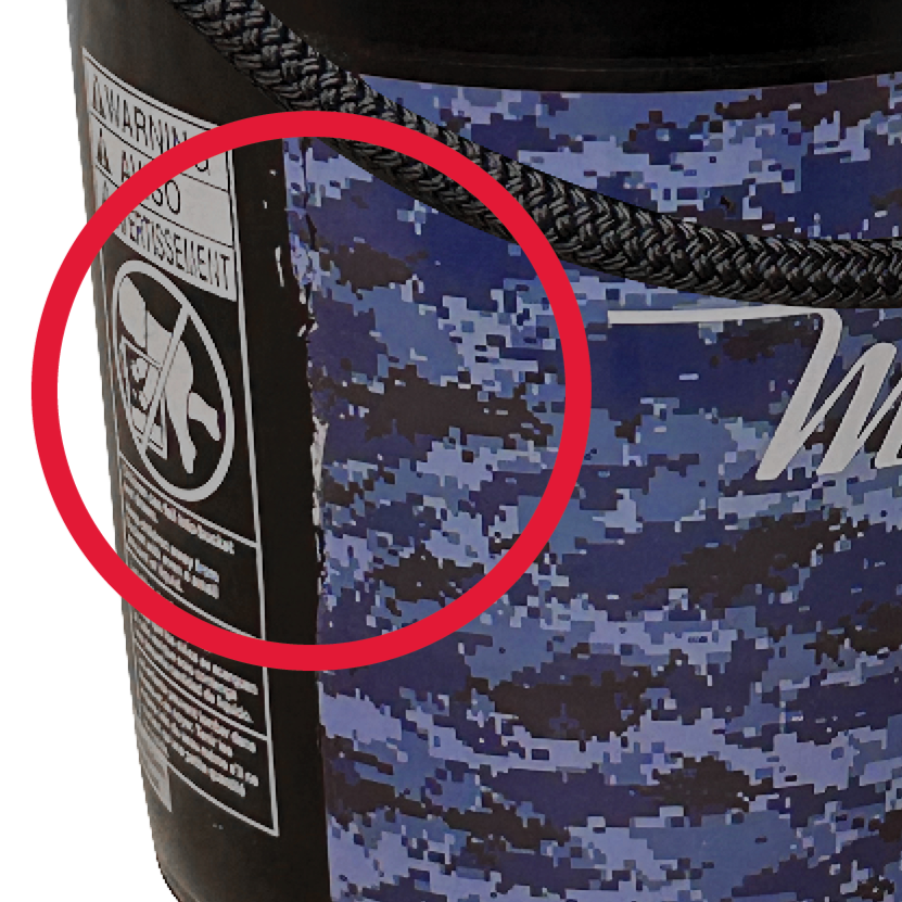 Close-up of a warning label on the blue camouflage-patterned SURPRISE BUCKET(2P) by Shurhold Industries, Inc., with a red circle on the safety icon. A thick black rope handle along the top edge ensures unbeatable value and durability.