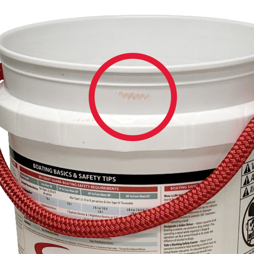 The ONE SURPRISE BUCKET by Shurhold Industries, Inc. features a red rope handle, a reddish-brown stain below the rim highlighted by a red circle, and boating safety instructions on its white label.