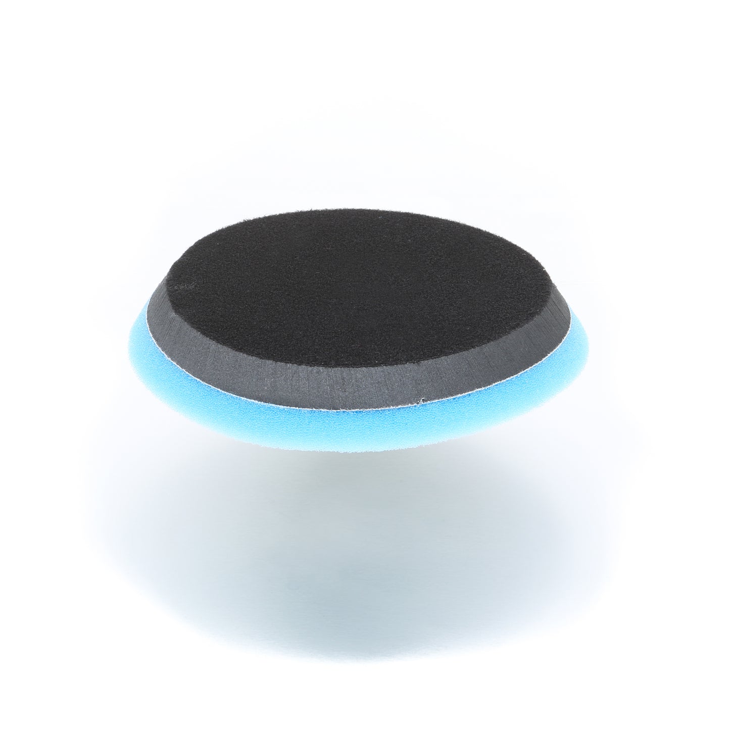 The Buff Magic Heavy Oxidation Pad by Shurhold Industries, Inc. is a round, flat cutting pad with a black top and blue foam bottom, ideal for removing oxidation when paired with Buff Magic; shown on a white background.