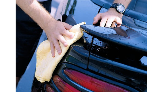 A man using a chamois to dry a car.