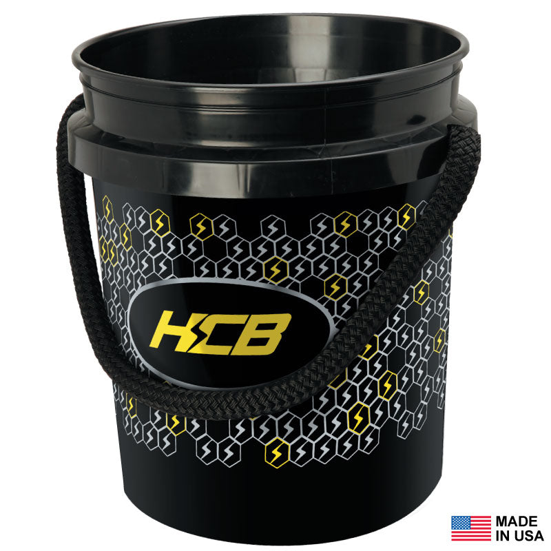 Black plastic bucket with a rope handle, decorated with a hexagonal pattern and yellow KCB logo; Made in USA label and small American flag shown in corner.